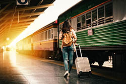 A girl from behind walkning with a suitecase on a trainstation